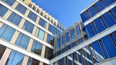 Mavi gökyüzünün altındaki tonlu cam ve çelik yapılardan yapılmış mavi perde duvarı. Bir binanın parçası..