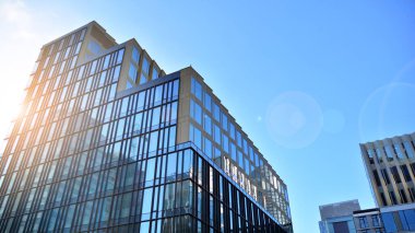 Mavi gökyüzünün altındaki tonlu cam ve çelik yapılardan yapılmış mavi perde duvarı. Binanın bir parçası. Parlak güneşli bir günde mavi gökyüzünde güneş ışınlarıyla cam cepheler..