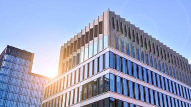 Mavi gökyüzünün altındaki tonlu cam ve çelik yapılardan yapılmış mavi perde duvarı. Binanın bir parçası. Parlak güneşli bir günde mavi gökyüzünde güneş ışınlarıyla cam cepheler..