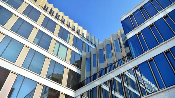 Mavi gökyüzünün altındaki tonlu cam ve çelik yapılardan yapılmış mavi perde duvarı. Bir binanın parçası..