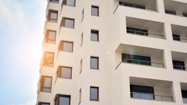 Modern çok katlı bir apartmanın dış cephesi, pencereleri ve balkonları..