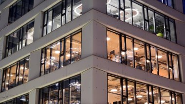 Ofis binalarının pencereleri gece aydınlandı. Şehir merkezinde yansıması olan cam mimari cephe tasarımı ile ışıklandırma.
