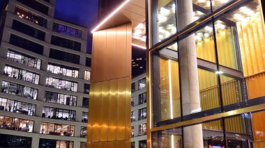 Ofis binalarının pencereleri gece aydınlandı. Şehir merkezinde yansıması olan cam mimari cephe tasarımı ile ışıklandırma.