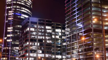 Ofis binalarının pencereleri gece aydınlandı. Şehir merkezinde yansıması olan cam mimari cephe tasarımı ile ışıklandırma.