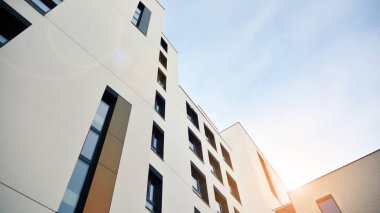Mavi gökyüzü olan güneşli bir günde modern apartman binaları. Modern bir apartmanın ön cephesi. Güneş ışığıyla cam yüzey.