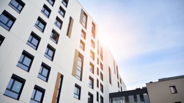 Mavi gökyüzü olan güneşli bir günde modern apartman binaları. Modern bir apartmanın ön cephesi. Güneş ışığıyla cam yüzey.