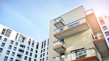 Mavi gökyüzü olan güneşli bir günde modern apartman binaları. Modern bir apartmanın ön cephesi. Güneş ışığıyla cam yüzey.