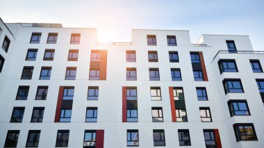 Mavi gökyüzü olan güneşli bir günde modern apartman binaları. Modern bir apartmanın ön cephesi. Güneş ışığıyla cam yüzey.