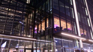 Ofis binalarının pencereleri gece aydınlandı. Şehir merkezinde yansıması olan cam mimari cephe tasarımı ile ışıklandırma.