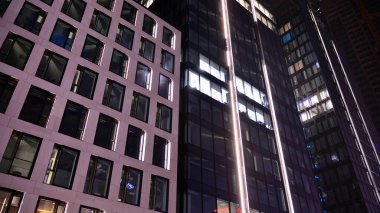 Ofis binalarının pencereleri gece aydınlandı. Şehir merkezinde yansıması olan cam mimari cephe tasarımı ile ışıklandırma.