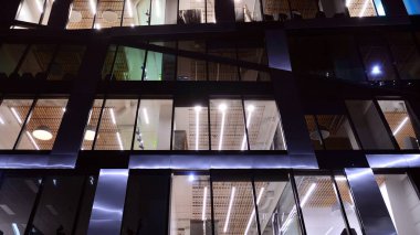 Ofis binalarının pencereleri gece aydınlandı. Şehir merkezinde yansıması olan cam mimari cephe tasarımı ile ışıklandırma.