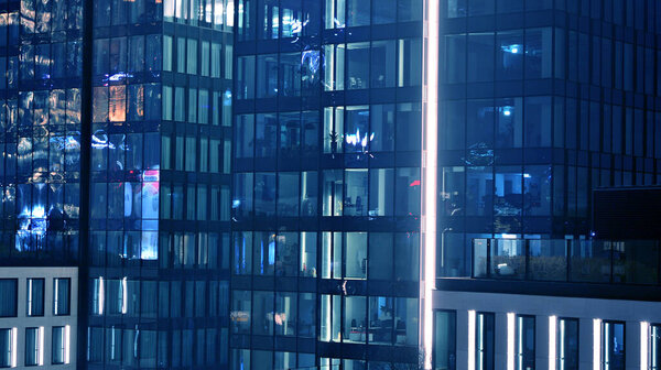 Pattern of office buildings windows illuminated at night. Lighting with Glass architecture facade design with reflection in urban city.