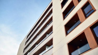 Yeni apartman cephesi. Cam balkon ve mavi gökyüzü arka planlı modern mimari binasının temiz görüntüsü..