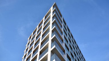 Yeni apartman cephesi. Cam balkon ve mavi gökyüzü arka planlı modern mimari binasının temiz görüntüsü..