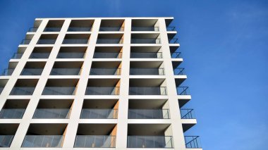 Yeni apartman cephesi. Cam balkon ve mavi gökyüzü arka planlı modern mimari binasının temiz görüntüsü..
