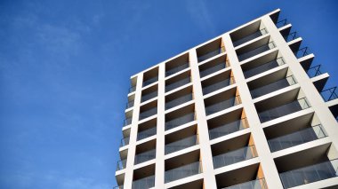 Yeni apartman cephesi. Cam balkon ve mavi gökyüzü arka planlı modern mimari binasının temiz görüntüsü..