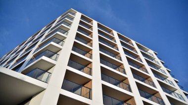 Yeni apartman cephesi. Cam balkon ve mavi gökyüzü arka planlı modern mimari binasının temiz görüntüsü..