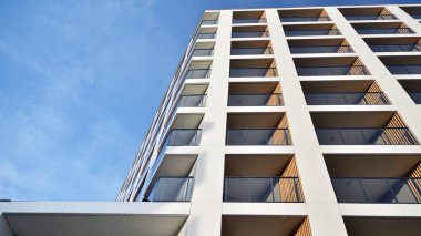 Yeni apartman cephesi. Cam balkon ve mavi gökyüzü arka planlı modern mimari binasının temiz görüntüsü..