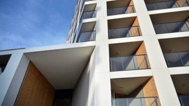 Yeni apartman cephesi. Cam balkon ve mavi gökyüzü arka planlı modern mimari binasının temiz görüntüsü..
