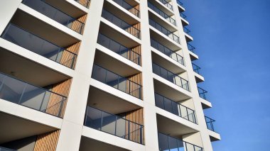 Yeni apartman cephesi. Cam balkon ve mavi gökyüzü arka planlı modern mimari binasının temiz görüntüsü..