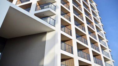Yeni apartman cephesi. Cam balkon ve mavi gökyüzü arka planlı modern mimari binasının temiz görüntüsü..
