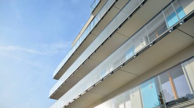 Yeni apartman cephesi. Cam balkon ve mavi gökyüzü arka planlı modern mimari binasının temiz görüntüsü..