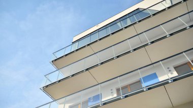 Yeni apartman cephesi. Cam balkon ve mavi gökyüzü arka planlı modern mimari binasının temiz görüntüsü..