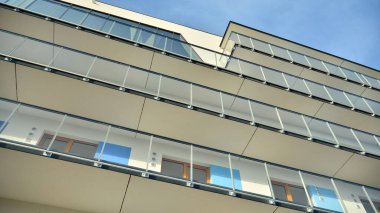 Yeni apartman cephesi. Cam balkon ve mavi gökyüzü arka planlı modern mimari binasının temiz görüntüsü..