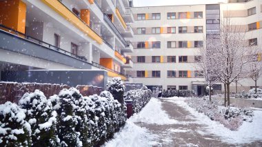 Fragment of modern apartment building on the background of winter  during a heavy snowfall. Snow is slightly shining clipart