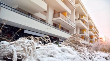 Yoğun bir kar yağışı sırasında kışın arka planındaki modern apartmanın bir parçası. Kar hafifçe parlıyor