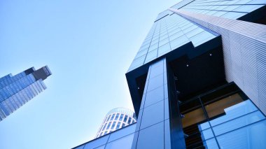 Mavi gökyüzü olan binaların cam cephesi. Şehir merkezindeki gökdelenler modern cam binaların arka planı.. 