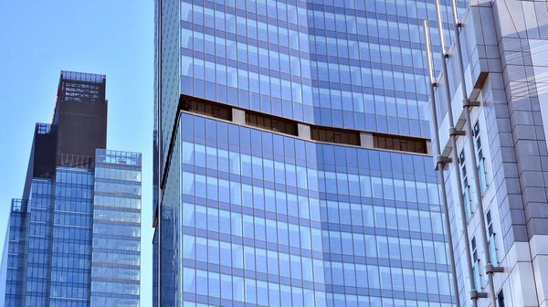 Glass facade of the buildings with a blue sky. Skyscrapers in the business city center.. Background of modern glass buildings.
