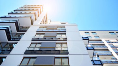 Mavi gökyüzü olan güneşli bir günde modern apartman binaları. Modern bir apartmanın ön cephesi. Güneş ışığıyla kaplı cam yüzey..