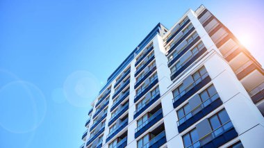 Mavi gökyüzü olan güneşli bir günde modern apartman binaları. Modern bir apartmanın ön cephesi. Güneş ışığıyla kaplı cam yüzey..