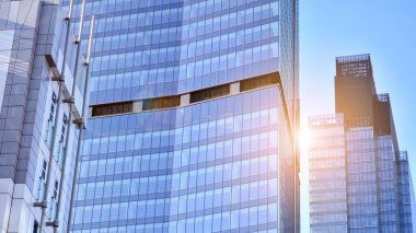 Şehir merkezindeki işletme bölgesi mimarisi. Mavi gökyüzüne ve güneş ışığına karşı cam yansıtıcı ofis binaları. Ekonomi, finans, iş faaliyeti kavramı.