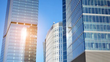 Şehir merkezindeki işletme bölgesi mimarisi. Mavi gökyüzüne ve güneş ışığına karşı cam yansıtıcı ofis binaları. Ekonomi, finans, iş faaliyeti kavramı.
