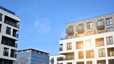 Mavi gökyüzü olan güneşli bir günde modern apartman binaları. Modern bir apartmanın ön cephesi. Güneş ışığıyla kaplı cam yüzey..