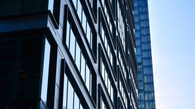 Mavi gökyüzüne karşı modern gökdelenlerin alt manzarası. Şehir merkezindeki iş binalarına bakıyorum..