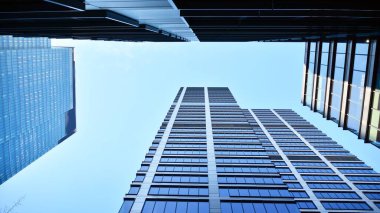 Mavi gökyüzüne karşı modern gökdelenlerin alt manzarası. Şehir merkezindeki iş binalarına bakıyorum..