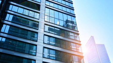 Mavi gökyüzüne karşı modern gökdelenlerin alt manzarası. Şehir merkezindeki iş binalarına bakıyorum. Ufukta yükselen güneş.