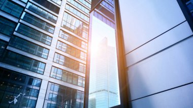 Mavi gökyüzüne karşı modern gökdelenlerin alt manzarası. Şehir merkezindeki iş binalarına bakıyorum. Ufukta yükselen güneş.