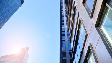 Mavi gökyüzüne karşı modern gökdelenlerin alt manzarası. Şehir merkezindeki iş binalarına bakıyorum. Ufukta yükselen güneş.