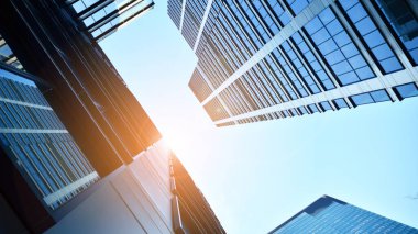 Mavi gökyüzüne karşı modern gökdelenlerin alt manzarası. Şehir merkezindeki iş binalarına bakıyorum. Ufukta yükselen güneş.