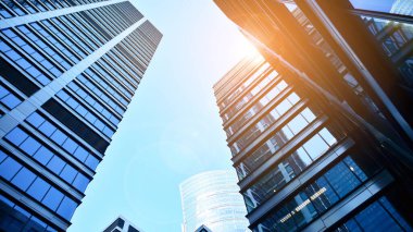 Mavi gökyüzüne karşı modern gökdelenlerin alt manzarası. Şehir merkezindeki iş binalarına bakıyorum. Ufukta yükselen güneş.