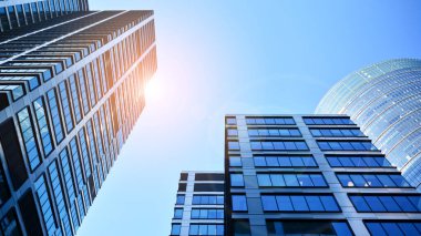 Mavi gökyüzüne karşı modern gökdelenlerin alt manzarası. Şehir merkezindeki iş binalarına bakıyorum. Ufukta yükselen güneş.