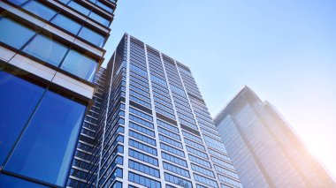 Şehir merkezindeki işletme bölgesi mimarisi. Mavi gökyüzüne ve güneş ışığına karşı cam yansıtıcı ofis binaları. Ekonomi, finans, iş faaliyeti konsepti. Ufukta yükselen güneş.