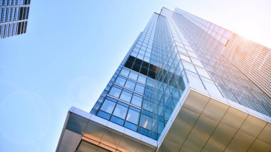 Şehir merkezindeki işletme bölgesi mimarisi. Mavi gökyüzüne ve güneş ışığına karşı cam yansıtıcı ofis binaları. Ekonomi, finans, iş faaliyeti konsepti. Ufukta yükselen güneş.