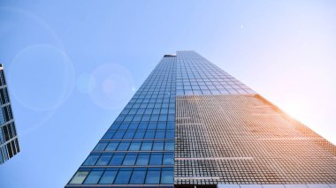 Şehir merkezindeki işletme bölgesi mimarisi. Mavi gökyüzüne ve güneş ışığına karşı cam yansıtıcı ofis binaları. Ekonomi, finans, iş faaliyeti konsepti. Ufukta yükselen güneş.