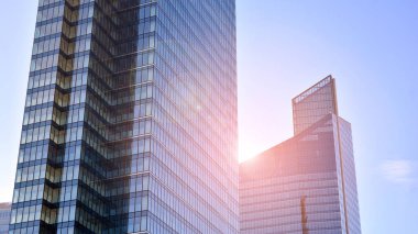 Şehir merkezindeki işletme bölgesi mimarisi. Mavi gökyüzüne ve güneş ışığına karşı cam yansıtıcı ofis binaları. Ekonomi, finans, iş faaliyeti konsepti. Ufukta yükselen güneş.