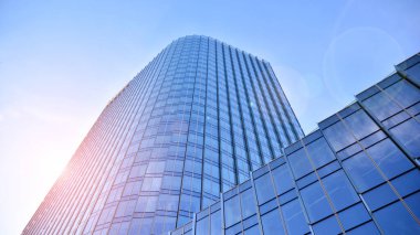 Şehir merkezindeki işletme bölgesi mimarisi. Mavi gökyüzüne ve güneş ışığına karşı cam yansıtıcı ofis binaları. Ekonomi, finans, iş faaliyeti konsepti. Ufukta yükselen güneş.